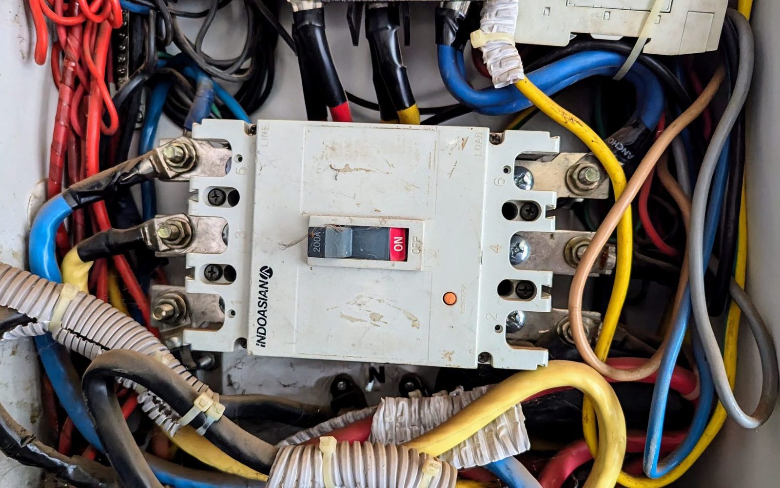A 200-amp service panel with the main breaker in the on position and colour-coded conductors landed on the bus.